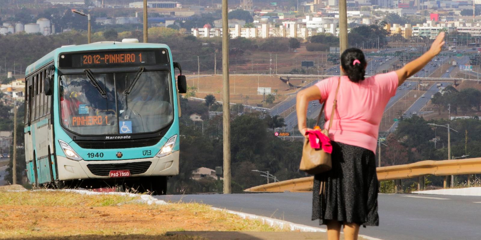 Mulher acena para um ônibus em via de Águas Claras, no Distrito Federal.