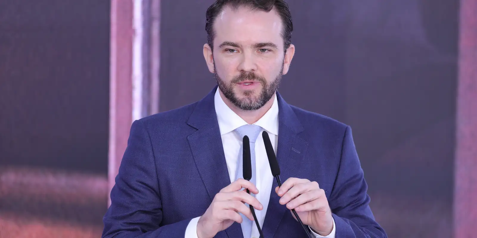 Dario Durigan fala diante de dois microfones