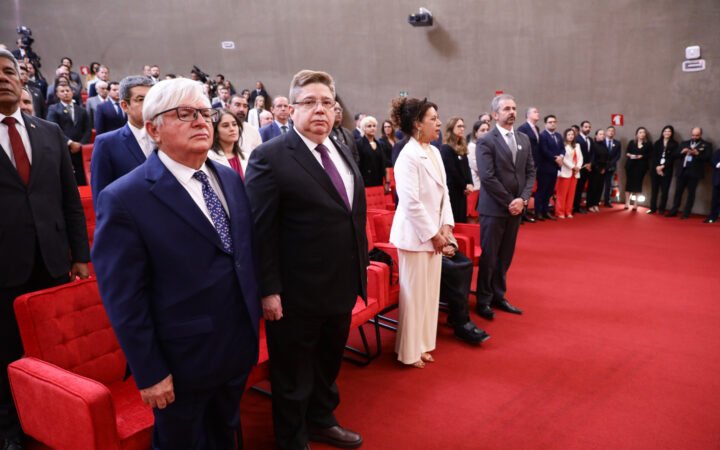 Estela Aranha, de roupa branca, e autoridades em solenidade no TSE, em fotografia de agosto de 2025.