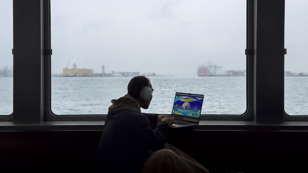 Pessoa utiliza um MacBook Pro junto a uma janela, em imagem de divulgação de 2023.